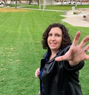 a woman standing in a park with her hands up