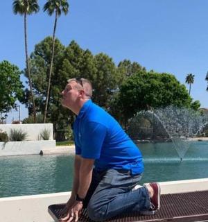 a man sitting on a bench in front of a fountain