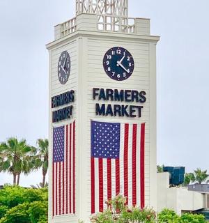 hodinová věž s americkou vlajkou a cedulí farmářského trhu