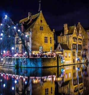 a city with christmas lights on the water at night