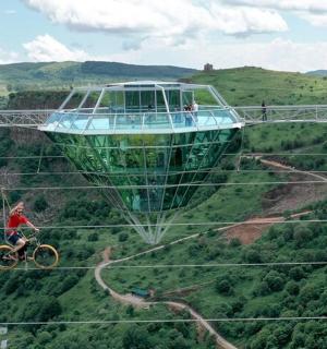 two people riding bikes on a suspension bridge with a boat