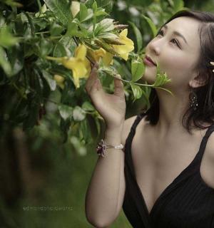 a woman in a black dress eating flowers from a tree