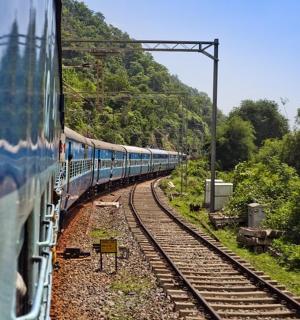 一列蓝色火车沿着山附近的铁轨行驶