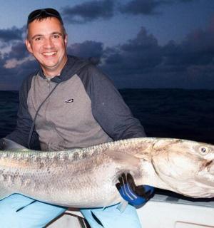a man sitting on a boat with a large fish