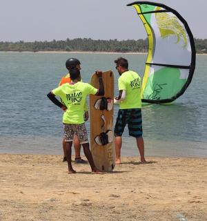 two men are standing on the beach with a surfboard