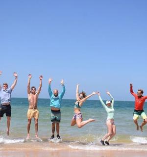 a group of people jumping in the water at the beach