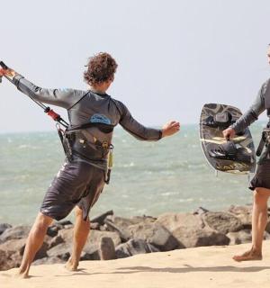 two people on the beach holding onto a rope