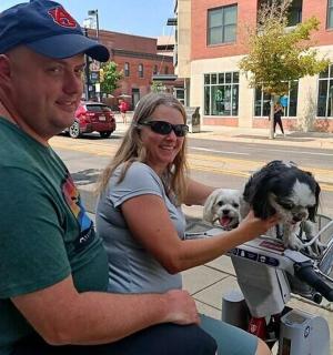 a man and a woman riding a motorcycle with two dogs