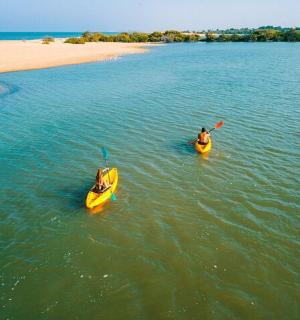 two people in kayaks in the water next to a beach