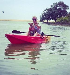 a woman sitting in a red boat with a dog
