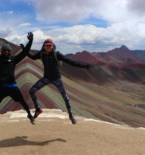 two people jumping in the air on top of a mountain