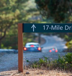 a street sign on the side of a road with a car