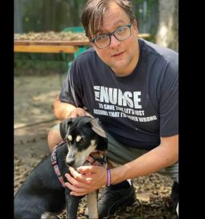 a man is squatting down with a dog