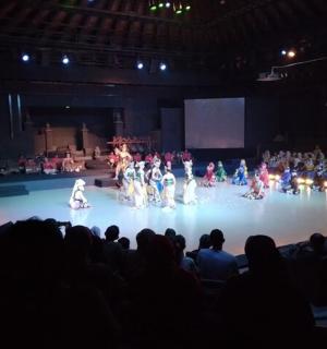 a group of people dancing on a stage in an auditorium