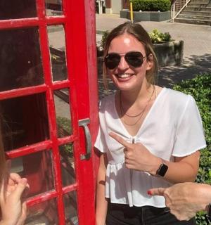 a woman standing next to a red phone booth