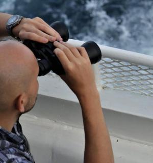 Muž drží na lodi dalekohled