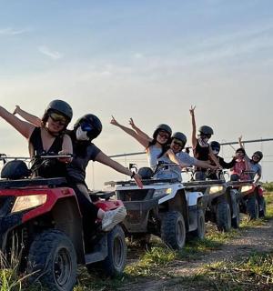 skupina lidí jedoucích na čtyřkolkách po nezpevněné cestě