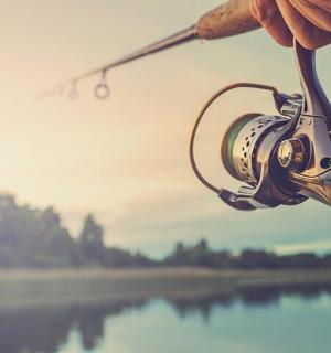 a person holding a fishing rod with a lake in the background