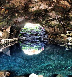 a cave with a pool of water in front