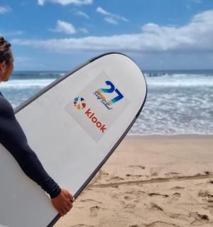 žena držící surfovací prkno na pláži