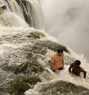 两名男子站在瀑布旁的水中