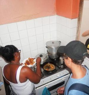 a woman taking a picture of two people cooking in a kitchen