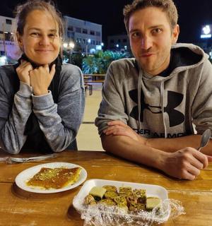 两个人坐在桌旁，桌上摆着一盘食物