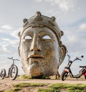 a large statue of a head with three bikes parked next to it