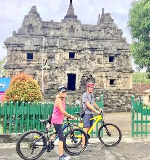 a man and a woman riding bikes in front of a building