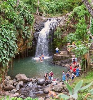 a group of people in a river with a waterfall
