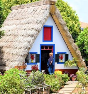 a man standing in front of a thatched house