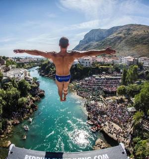 muž skákající do řeky s rozpaženýma rukama