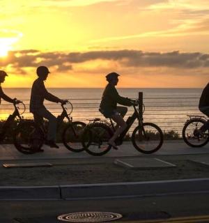 一群人在海边的人行道上骑自行车