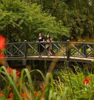 dvě ženy stojící na mostě přes řeku