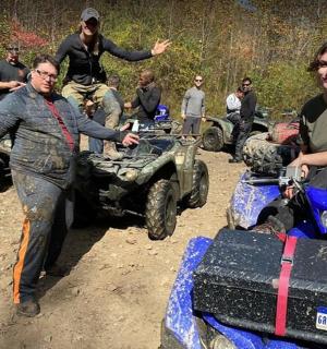 a group of people standing in the dirt with atvs