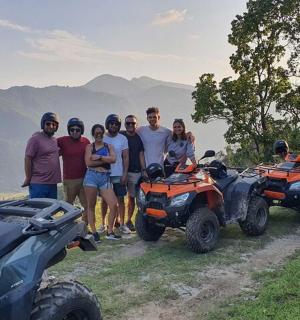 skupina lidí stojících vedle čtyřkolek na hoře