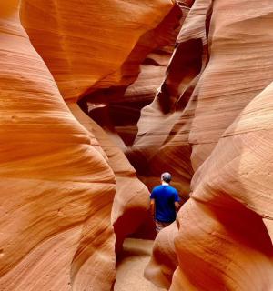 a man is walking through a slot canyon