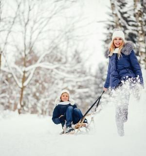 žena táhne dítě na saních ve sněhu