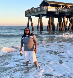 a man standing in the ocean in front of a pier
