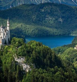 a castle on top of a mountain with a lake