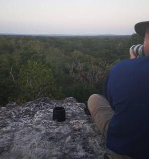 a man sitting on a rock talking on a cell phone