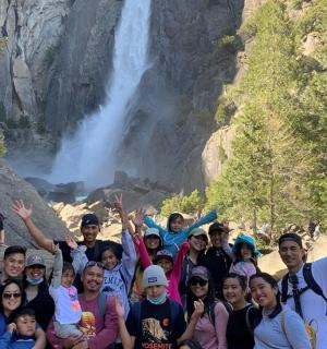a group of people posing in front of a waterfall