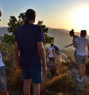 山の上に立って夕日を眺める人々のグループ