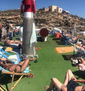 skupina lidí sedících v zahradních křeslech na pláži