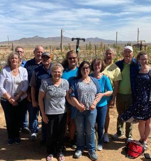 a group of people posing for a picture in a vineyard