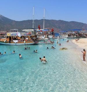 a group of people in the water at a beach with boats