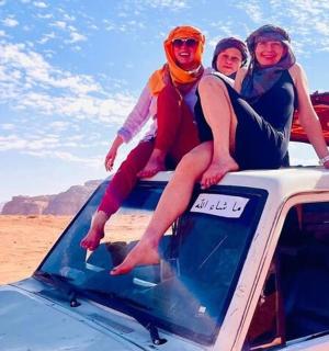 three people sitting on the roof of a truck in the desert