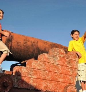 two young children standing on top of austedusted pipe