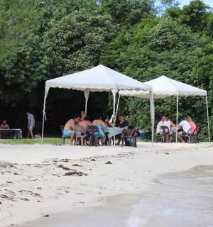 一群人坐在海滩的白色帐篷下