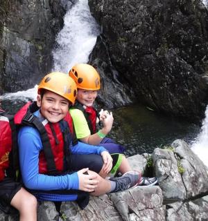 tři lidé v helmách sedící na skalách poblíž vodopádu